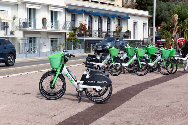 Nice, France - June 12, 2024: A row of Lime bikes neatly parked by the trowalk in Nice. Эти зеленые и белые велосипеды являются частью услуги совместного использования велосипедов, способствуя экологически чистых транспортных средств. Жилые здания можно увидеть на заднем плане