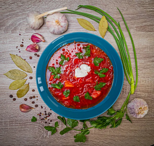 stock image Traditional ukrainian borsch on wooden background. Red beet soup with sour cream and parsley. Ukrainian national cuisine. Flatlay.