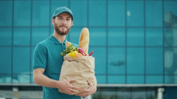 Portret Przystojnego Dostawcy Jednorodnej Torbie Papierowej Żywnością Uśmiechnięty Kurier Pokazuje — Wideo stockowe