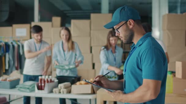 Man Vrijwilliger Schrijven Klembord Terwijl Werken Food Bank Pakhuis Jongeman — Stockvideo
