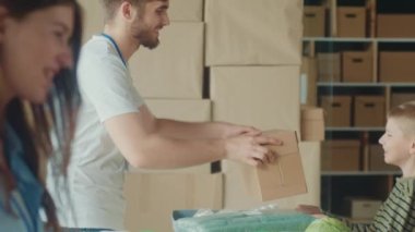 Sosyal Yardım Konsepti: Gönüllü Yardım Merkezinde Bir Çocuk Dağıtım veya Mülteci Yardım Merkezi 'nde Arkadaş Canlısı Gönüllüden Bir Kutu Yiyecek Aldı.