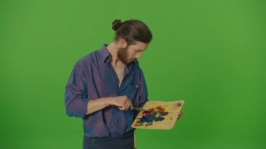 Genç Sakallı Adam Palette Boya Karıştırıyor, Renge İhtiyacı Var, Yeşil Ekranda Eşsiz Renk Kombinasyonları Araştırıyor, Krom Anahtar. Yaratıcılık ve Sanat Konsepti