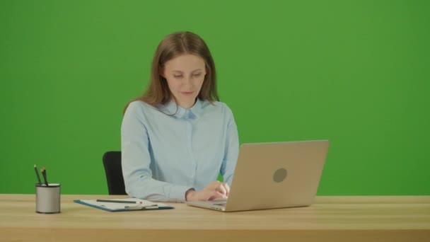 绿色屏风 年轻漂亮的有动力的学生在笔记本电脑上打字上网 上网工作 在工作台上浏览网站 远程工作概念 网上学习概念 — 图库视频影像