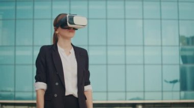 Sanal Gerçeklik Kulaklığı Giyen Kadın Mühendis Mavi Pencereli Bir Binanın Yanındayken Artırılmış Gerçeklikte Çalışır ve Jestler Yapar. VR Dönüşümü.