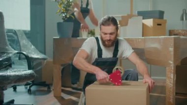 İşçi İşçi Mühürleme Karton Kutusu Koli Bant Makinesi kullanıyor. Profesyonel Paketleme ve Boşaltma Hizmetleri. Taşınmak için toplanma ve hazırlık. Malzemeler ve Malzemeler Paketleniyor