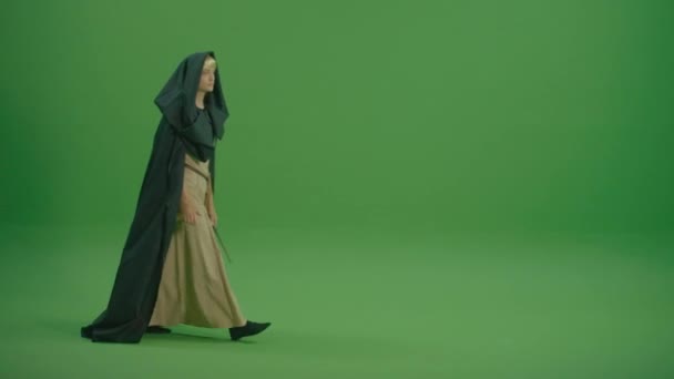 緑の画面 少女は魔法の杖を手に歩く 中世のドレスに身を包んだ深刻な女性の容態とフード付きのクロークが呪文を唱える 魔女と謎 — ストック動画