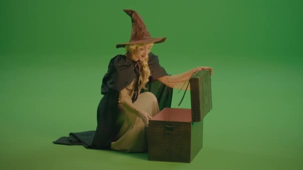 绿色屏风 一个穿着中世纪服装的魔法女孩打开了魔法的胸膛 拿出了魔法的魔杖 等待奇迹的到来 魔术物品 镜子及其他手工艺品 — 图库视频影像