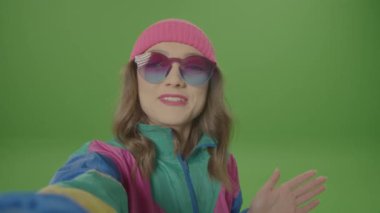 Yeşil Ekran. 80-90 'ların Gülümseyen Kızı Pembe Şapkalı ve Güneş Gözlüklü Selfie Yapan, Kameraya Dengeli. Gençlik ve İnternet kavramı, Blogger Girl
