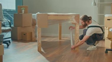 Üniformalı Taşımacılık İşçileri Mobilyaları Dikkatlice Paketliyor. Mobilya, ekipman sökme ve montaj. Seyahat sigortası. Çalışan İşçi Takımı Müşterilerin Taşımasına Yardım Ediyor.