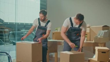 Üniformalı Taşımacılık İşçileri Kutuları dikkatlice açıyor. Nakliye ve Paketleme İşletme Hizmetleri Şirketi. Servisler Yükleniyor ve Boşaltılıyor