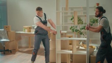 Mobilya taşıyan üniformalı nakliye şirketinin çalışanları. Çalışanlardan oluşan ekip, müşterilerin taşınmasına yardım ediyor. Yerel Taşıma Hizmetleri
