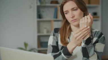 Dizüstü bilgisayarla Masa 'da Odaklanmış Kadın Bir anda El Ağrısı Hissediyor. Uzun süreli yaşam tarzından bıkmış bir kadın. Rahatlamaya çalış ve eline masaj yaparak acını dindir. Ofis Sendromu.