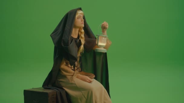 绿色屏风 一个戴着头巾的女魔头 穿着中世纪服装 头戴灯笼的女魔头 遥望远方 魔法森林 一个神秘而神秘的世界 — 图库视频影像