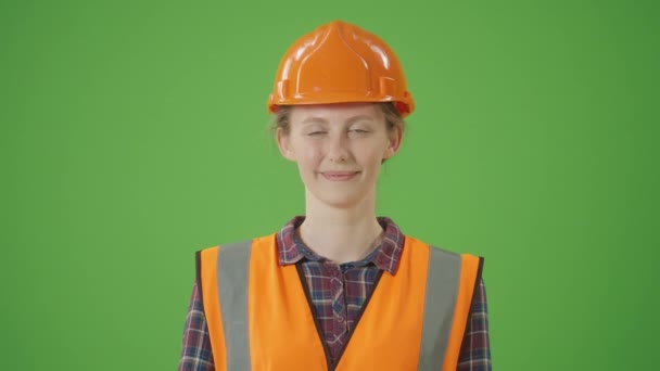 绿色屏风 年轻自信的女建筑工人 穿着格子衬衫 安全夹克 助听器 带着清洁漆辊在脸上打滚 闭上双眼 — 图库视频影像