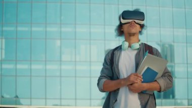 Üniversitenin arka planında VR kulaklık takan motive olmuş genç bir öğrenci. Sanal Gerçeklik Öğrenme Konsepti. Dijital Eğitim. Eğitimde yenilikler. Gelecek Teknolojileri