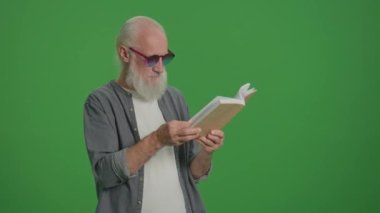 Yeşil Ekran. Kitap okuyan, gri sakallı ve komik gözlüklü zeki bir ihtiyarın portresi. Yaşlı bir adam bir kitabın sayfalarını karıştırır. Boş zaman, Hobi Konsepti.