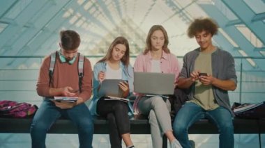 Smartphone kullanan bir grup öğrenci bankta oturuyor ve akıllı telefonlarını daktilo ediyor. Ayrıl. Dijital Eğitim, Gelecek Teknolojileri, Öğrenmenin Robotlaştırılması, Küresel Eğitim