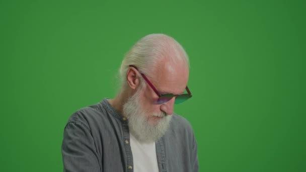 绿色屏风 一个留着灰胡子和滑稽眼镜的老人正在用老式电话交谈 收集及保存旧电话机 — 图库视频影像