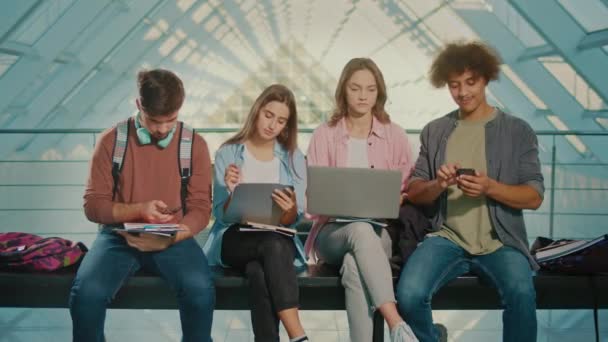 学生使用智能手机组 学生坐在长椅上 在智能手机上打字 休息一下数字教育的概念 未来技术 学习的机器人化 全球教育 — 图库视频影像
