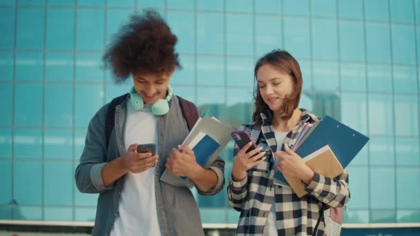 2人の魅力的な学生が大学ヤードでスマートフォンを話して使用しています デジタル教育 将来の技術 チームワークだ 学習段階の完了 — ストック動画