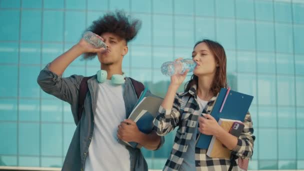 Twee Aantrekkelijke Studenten Met Boeken Drinken Water Uit Fles Achtergrond — Stockvideo