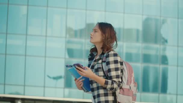 Pretty Student Girl Χρησιμοποιώντας Ένα Smartphone Ενώ Περπάτημα Βιβλία Σχετικά — Αρχείο Βίντεο