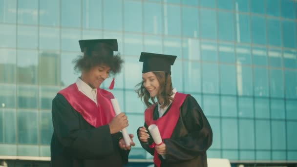 Happy Graduates Mantle Caps Conversando Fundo Universidade Com Diplomas Graduados — Vídeo de Stock