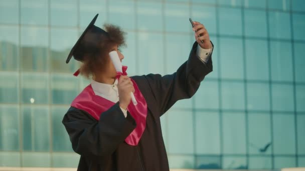 Gülümseyen Erkek Mezuniyet Töreni Diplomalı Siyah Elbise Pozu Selfie Çekiyor — Stok video