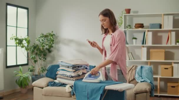 Evde Ütü Ütüleyen Kadınları Yorgunum Giysileri Ütülemekten Sıkıldığı Için Telefonunu — Stok video