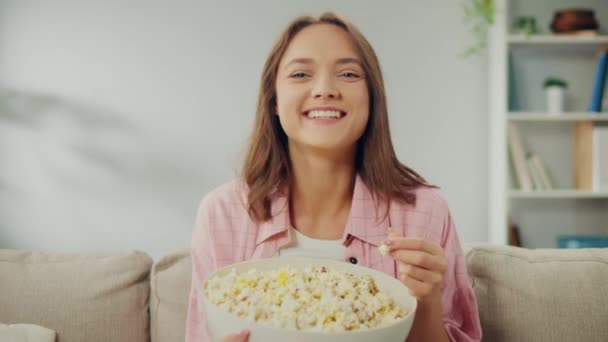 Счастливая Молодая Женщина Сидит Диване Ест Попкорн Смотрит Телевизор Веселая — стоковое видео