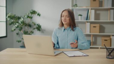 Gülümseyen genç bir kadın iş yerinden biriyle konuşuyor. Başarılı bir Serbest Kadın, İş Sorunları Üzerine Bir Video Yayını Yapıyor. Uzak Çalışma için Teknolojik Araçlar.
