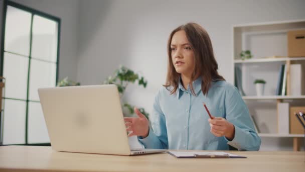 一个愤怒的年轻女人正在通过工作中的视频电话与某人交谈 一名女自由撰稿人主持了关于工作问题的视频广播 她解决工作中的问题 远程工作的技术工具 — 图库视频影像