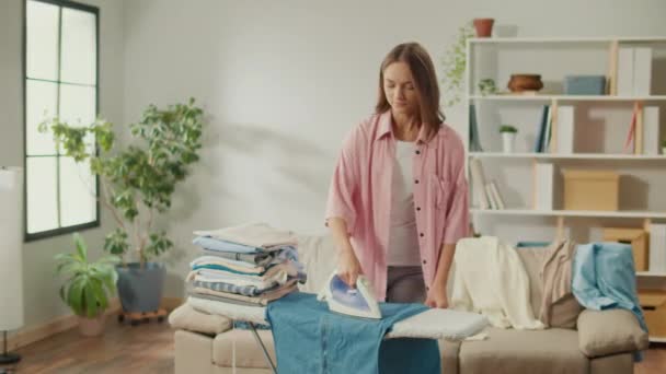 Χαμογελώντας Νεαρή Νοικοκυρά Γυναίκα Απολαμβάνει Ρούχα Σιδερώματος Στο Σπίτι Μια — Αρχείο Βίντεο