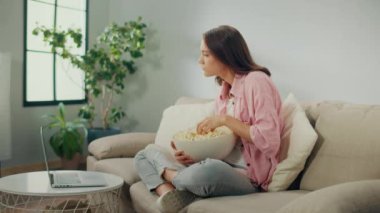 Patlamış mısır yiyen ve dizüstü bilgisayardaki filmi izlemeye odaklanan genç bir kadın. Kanepede oturan ve çok ilginç bir film izleyen ciddi bir kadın. Film Türleri ve Duygusal Tepkiler.