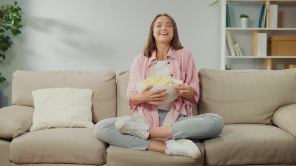 Счастливая Молодая Женщина Сидит Диване Ест Попкорн Смотрит Телевизор Веселая — стоковое видео