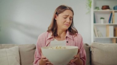 Koltukta oturan, patlamış mısır yiyen ve korku filmi izleyen genç bir kadın. Filmdeki Beklenmedik Anlar 'dan Korkmuş Patlamış Mısır Döküyor. Film Türleri ve Duygusal Tepkiler.