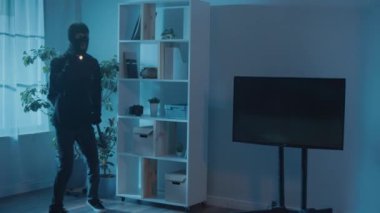 Siyah Giysili Soyguncu ve Maskeli Ev 'e Girdi. Elinde el feneri ve levyesi olan bir suçlu. Gece görüş gözetim kameraları. Kablosuz gözetleme kameraları. Bulut Güvenlik Sistemleri