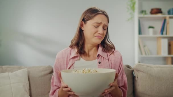 一个年轻女人坐在沙发上 吃爆米花 看恐怖片 恐惧的爆米花 来自电影中意想不到的时刻 电影类型和情感反应 — 图库视频影像