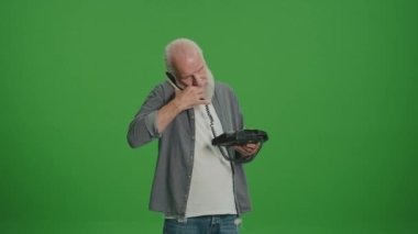 Yeşil Ekran. Gri sakallı yaşlı bir adam antika bir telefonla konuşuyor. Eski telefonları topluyor ve koruyor..