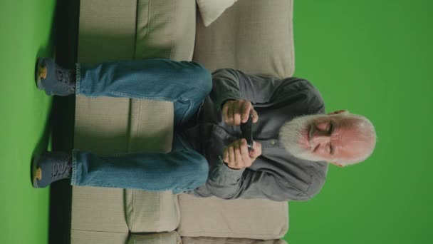 Зеленый Экран Вертикали Старик Седой Бородой Играет Компьютерные Игры Джойстиком — стоковое видео