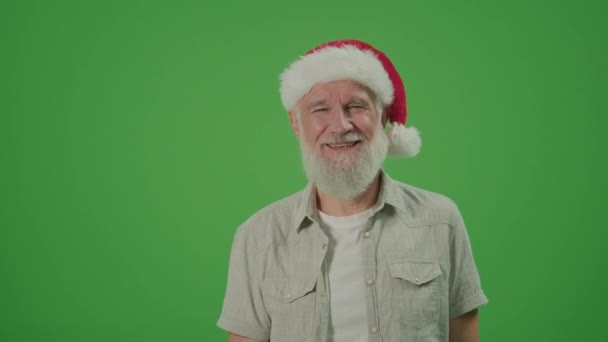 緑の画面 サンタ ハットにグレーの髭を生やしたハッピー オールド マンが親指を上げている 高齢者の親戚と一緒に旅行する 休日配送コンセプト — ストック動画