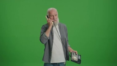Yeşil Ekran. Gri Sakallı Yaşlı Adam Birisiyle Eski Telefon ve Quarrels Konuşuyor. Eski Telefonları Topluyor ve Koruyor.