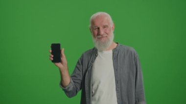 Yeşil Ekran. Akıllı telefonlu gülümseyen yaşlı bir adamın portresi. Yaşlılar için Gelişen Teknolojiler. Market Evleri ve Yaşlılar İçin Şeyler İnterneti.