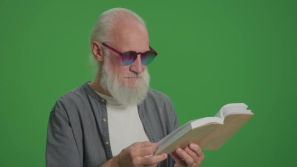绿色屏风 一个长着灰胡子和滑稽眼镜的聪明老人的画像 一个老年人翻阅着一本书的书页 康乐活动 康乐活动概念 — 图库视频影像