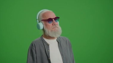 Yeşil Ekran. Komik Gözlüklü Modern Yaşlı Adam Kulaklıkla Müzik Dinliyor. Yaşlılar için Gelişen Teknolojiler.