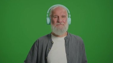 Yeşil Ekran. Gri Sakallı Mutlu Yaşlı Bir Adamın Portresi Kulaklıkla Müzik Dinliyor ve Dans Ediyor. Yaşlılar İçin Gelişen Teknolojiler.