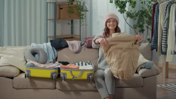 Uśmiechnięta Młoda Kobieta Podróżująca Kapeluszu Zbiera Ubrania Podróż Pakuje Rzeczy — Wideo stockowe