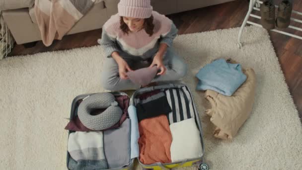 帽子の若い女性旅行者のトップビューは旅行のための服を集め 家でスーツケースに物事を詰め込みます 旅行の必需品 冬の冒険 — ストック動画