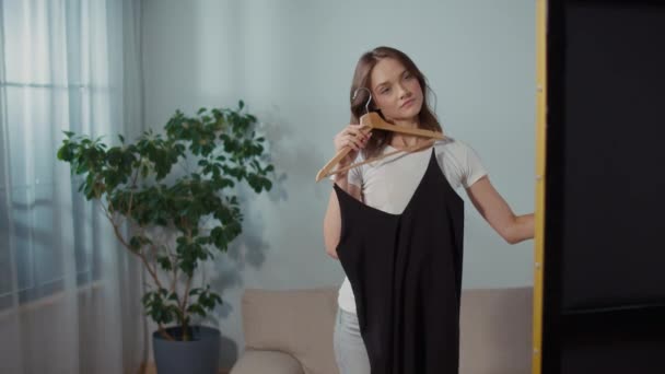 Улыбчивая Молодая Женщина Выбирает Платье Перед Зеркалом Социальная Реклама — стоковое видео