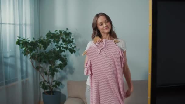Uśmiechnięta Młoda Kobieta Wybiera Sukienkę Przed Lustrem Ładna Dziewczyna Szykuje — Wideo stockowe